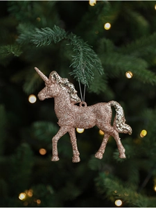 Close-up of pink glitter unicorn ornament hanging on a festive green Christmas tree branch