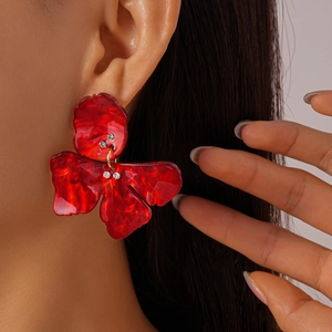 Close-up of model wearing red marble resin flower earrings with gold accents and rhinestones