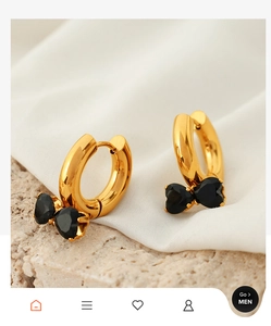 Detailed close-up of golden hoop earrings featuring elegant double black heart stones