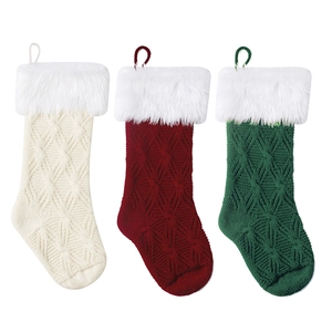Drei gestrickte Weihnachtsstrümpfe mit weißem Kunstpelzrand in Rot, Grün und Weiß
