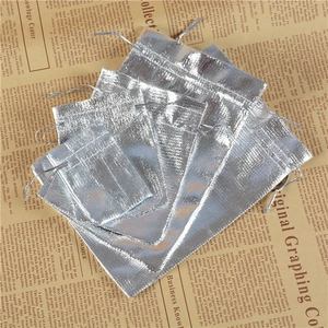 Detailed view of silver drawstring gift pouches with metallic texture on vintage newspaper