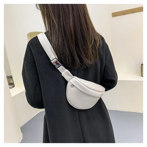 Detail of minimalist beige half-moon chest bag with adjustable strap and metal buckle