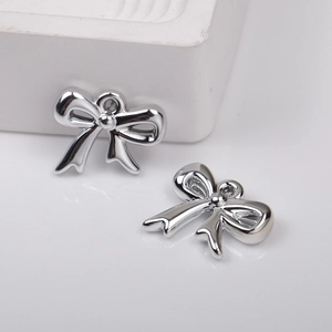 Macro detail of polished silver bow-shaped charms with metallic mirror finish for DIY jewelry