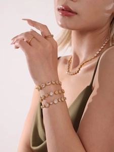 Detail showing stacked gold plated bracelets with sparkling zircon stones on model's wrist