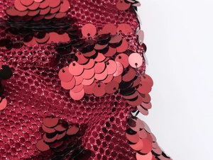 Macro shot of red sparkling sequins on a mesh fabric base for party dresses