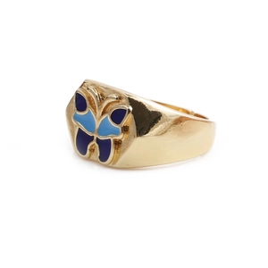 Detailed view of a golden ring featuring vibrant blue enamel butterfly wings on a white background