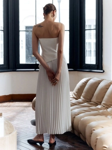 Completo bianco con top a fascia e gonna lunga a pieghe in un ambiente di lusso