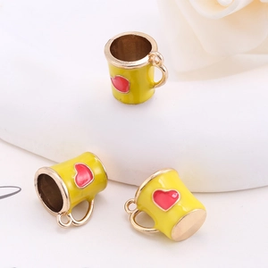 Macro shot of three yellow mug charms with red hearts and gold handles for jewelry DIY