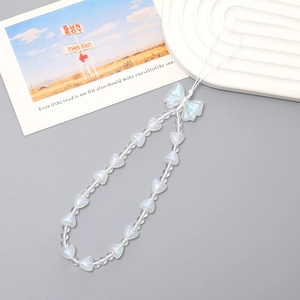 Close-up of beaded phone charm with iridescent bow and white heart beads on a clean surface