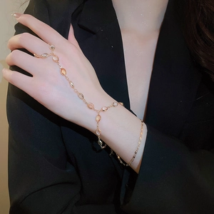 Detail of gold ring bracelet set with light oval gemstones and small pearls on model