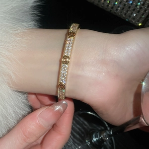 Gros plan du bracelet doré serti de zircons avec des motifs géométriques ajourés circulaires