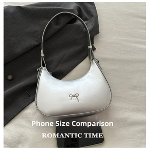 Silver metallic hobo bag detail with metal bow accent and smartphone for scale