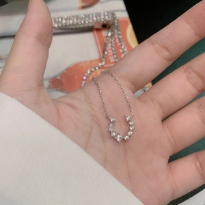 Macro shot of U-shaped silver necklace pendant featuring sparkling multi-shaped zircons