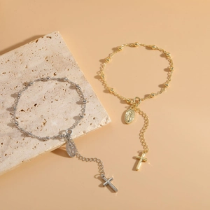 Detail of 14K gold and silver beaded cross bracelets with Virgin Mary medals on stone