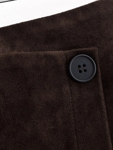 Makro-Detail von braunem Wildleder-Stoff mit weicher Textur und mattem Knopf