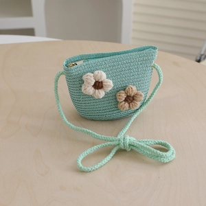 Close-up of mint green woven straw crossbody bag with handmade crochet flower details