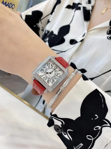 Detalle del reloj cuadrado con diamantes, correa de cuero rojo y brazalete de plata