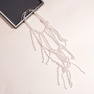 Detailed view of layered faux pearl body chain with golden mesh fringe and tassels