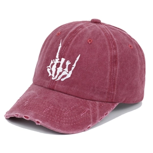 Detailed close-up of distressed brim and bone hand embroidery on burgundy cotton cap