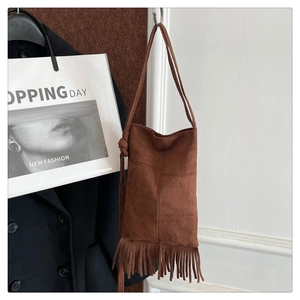 Detailed close-up of brown suede shoulder bag featuring long retro tassel fringe and knot strap