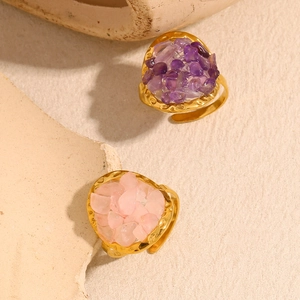 Dettaglio di anelli placcati oro 18K con intarsi di pietre rosa e viola su beige
