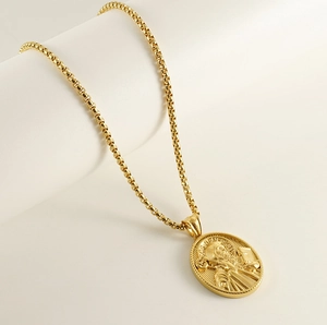 Detailed macro of a 18K gold-plated oval St. Benedict pendant on a box chain