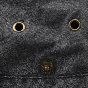 Macro view of washed cotton fabric with vintage bronze eyelets and snap button details