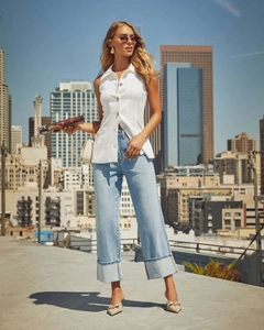 Detail of high waisted light blue straight jeans with wide fold-up cuffs and white top