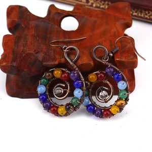 Detail view of handmade copper wire spiral earrings with colorful natural crystal beads