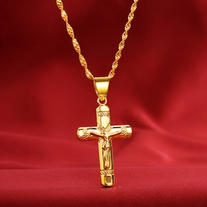 Close-up of golden crucifix Jesus pendant with textured twist chain on red velvet