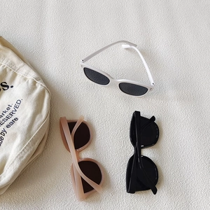 Three retro oval children sunglasses in white, matte pink and black on fabric