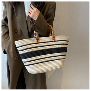 Detail of hand-woven tote bag with natural bamboo handles and chic black white stripes
