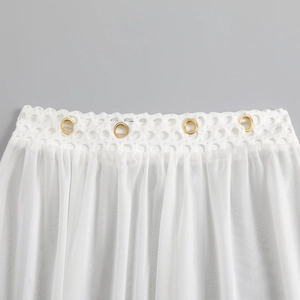 Close-up of white mesh swimsuit featuring crochet lace detail and gold grommets