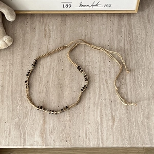 Detail of woven Bohemian waist belt featuring dark wooden beads and metallic spacers