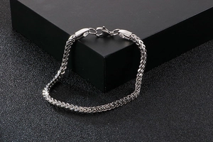 Detailed view of silver stainless steel Franco chain bracelet with lobster clasp on black leather