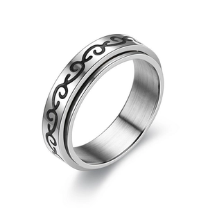 Close-up of stainless steel spinner ring with etched black wave patterns on silver surface