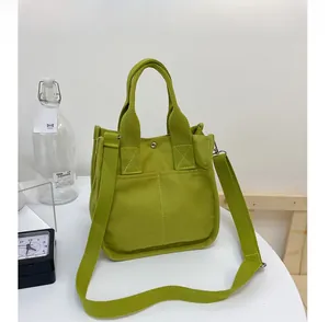 Detail of green canvas tote showing the reinforced handle and front slip pocket design