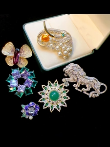 Detailed arrangement of luxury brooches with purple crystals and emerald gems on velvet