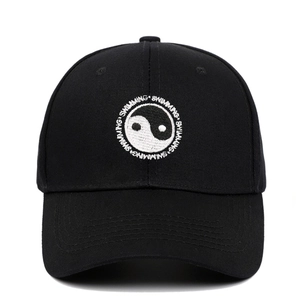 Close-up of Yin Yang embroidery and 'SWIMMING' text on a black cotton baseball cap