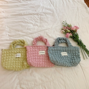 Detailed macro view of three quilted bubble tote bags in pastel yellow, pink, and blue colors