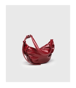 Detail of burgundy pleated dumpling bag showing glossy faux leather texture and soft folds
