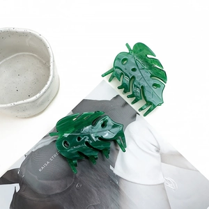 Detailed close-up of two green acetate Monstera leaf hair claws with marble texture