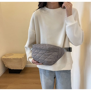 Detail of grey quilted waist bag with adjustable strap and buckle on model
