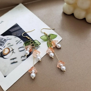 Close-up of pink bellflower earrings with green leaves and elegant white pearl details