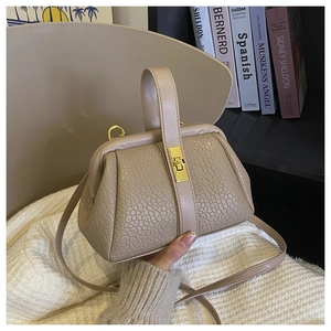 Khaki pebbled leather handbag with metal buckle closure held over a beige knit