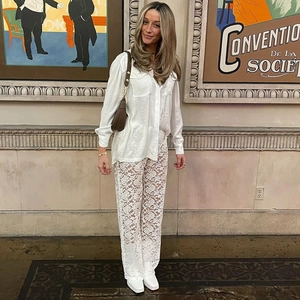 Dettaglio dei pantaloni in pizzo bianco a vita alta con pannelli trasparenti e camicia coordinata