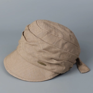 Close-up of khaki linen cap fabric texture with a bronze metal logo plate detail