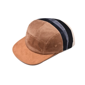 Close-up of assorted corduroy baseball caps in brown, blue, grey and beige stacked together