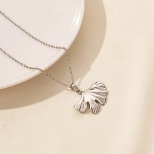 Macro view of silver ginkgo leaf pendant showing detailed vein texture on cross chain