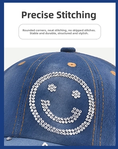 Macro shot of blue denim baseball cap featuring sequined smiley face and orange topstitching